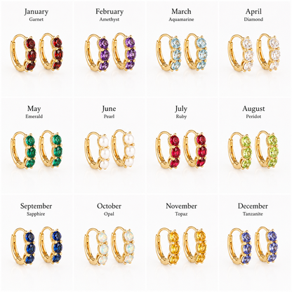 A 12-grid jewelry chart showing gold huggie hoop earrings with gemstone rows labeled by month and gem name. The earrings include garnet, amethyst, aquamarine, diamond, emerald, pearl, ruby, peridot, sapphire, opal, topaz, and tanzanite in gold-tone settings.